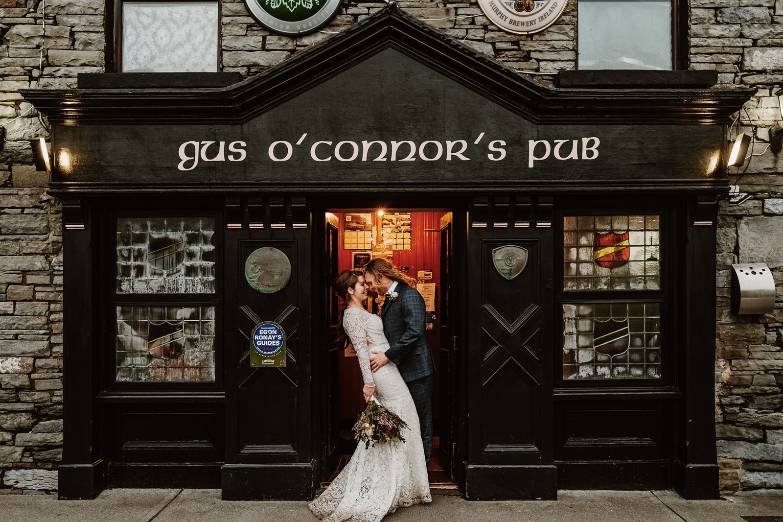 Bride and groom kiss outside an Irish pub in Doolin, Ireland