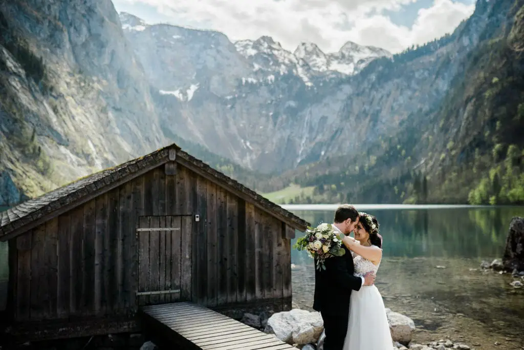 Bride and groom embrace in front of the Konigsee in Berchtesgaden National Park in Germany