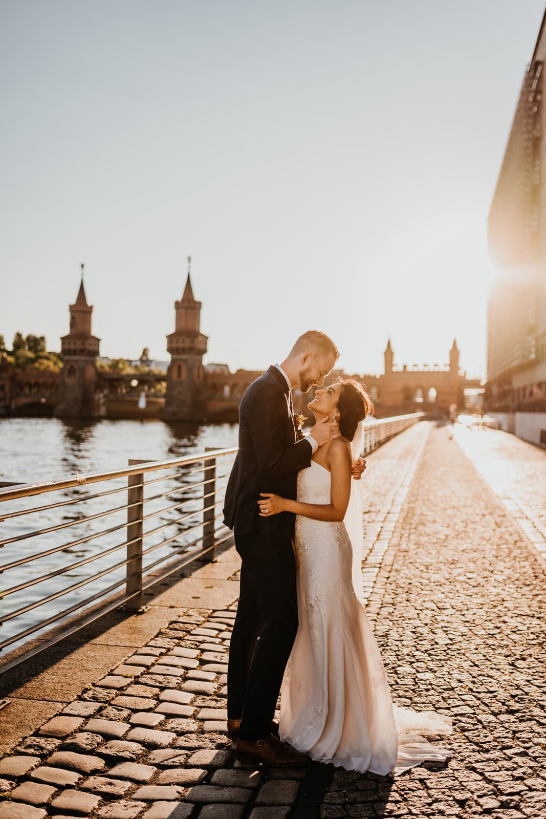 Bride and groom kiss at sunset by a river in Berlin