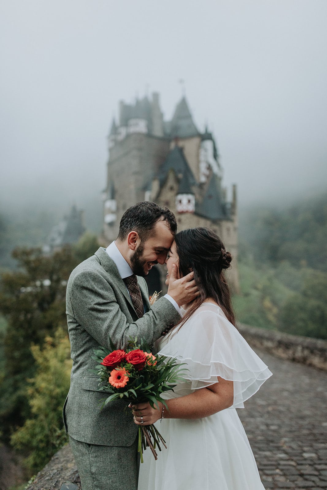Brinde and groom embrace in the mist outside Burg Eltz Castle in Germany