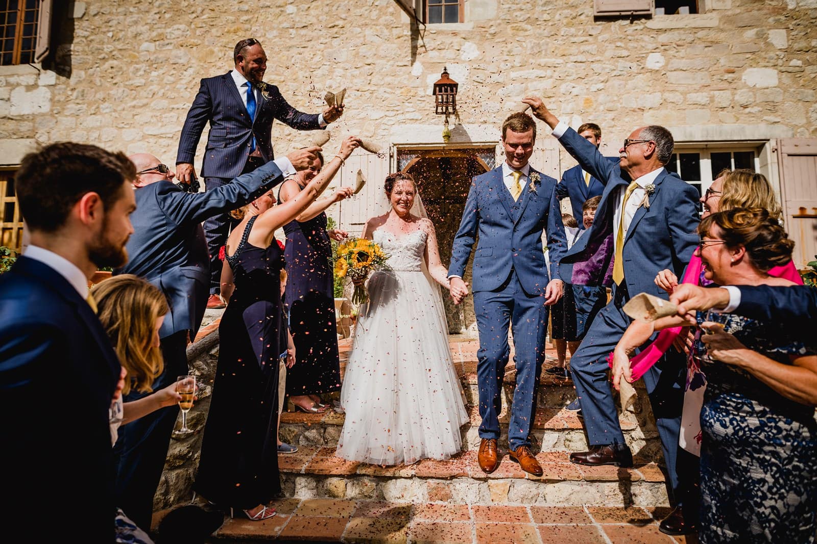 Bride and groom exit to confetti in the grounds of Chateau de Brametourte in France