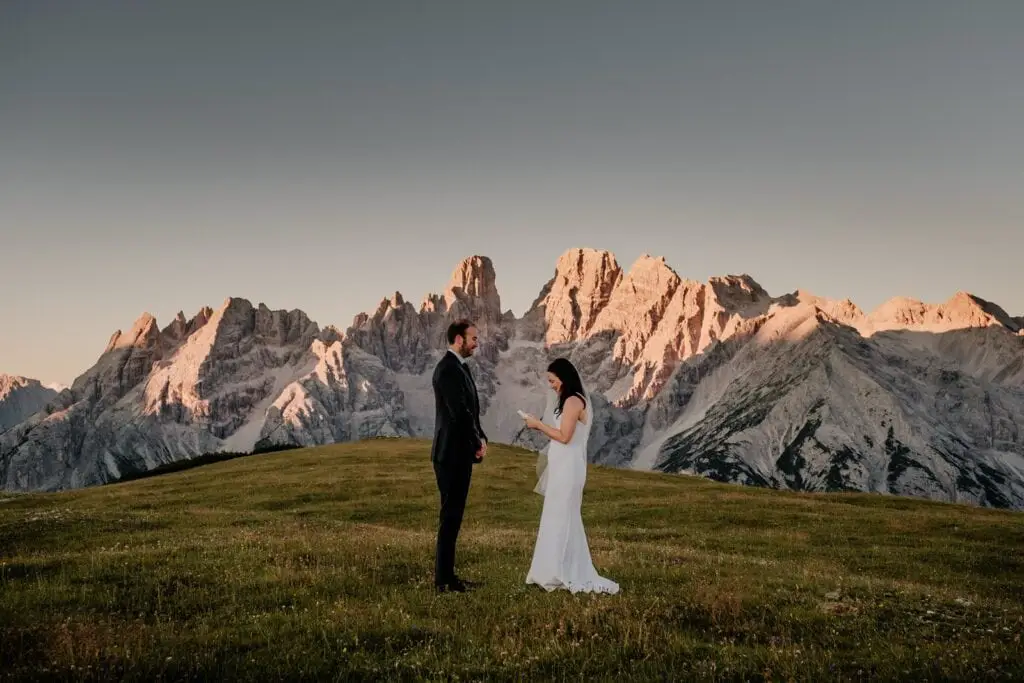 The sun illuminates the peaks of the Dolomites as a bride and groom exchange wedding vows at sunrise