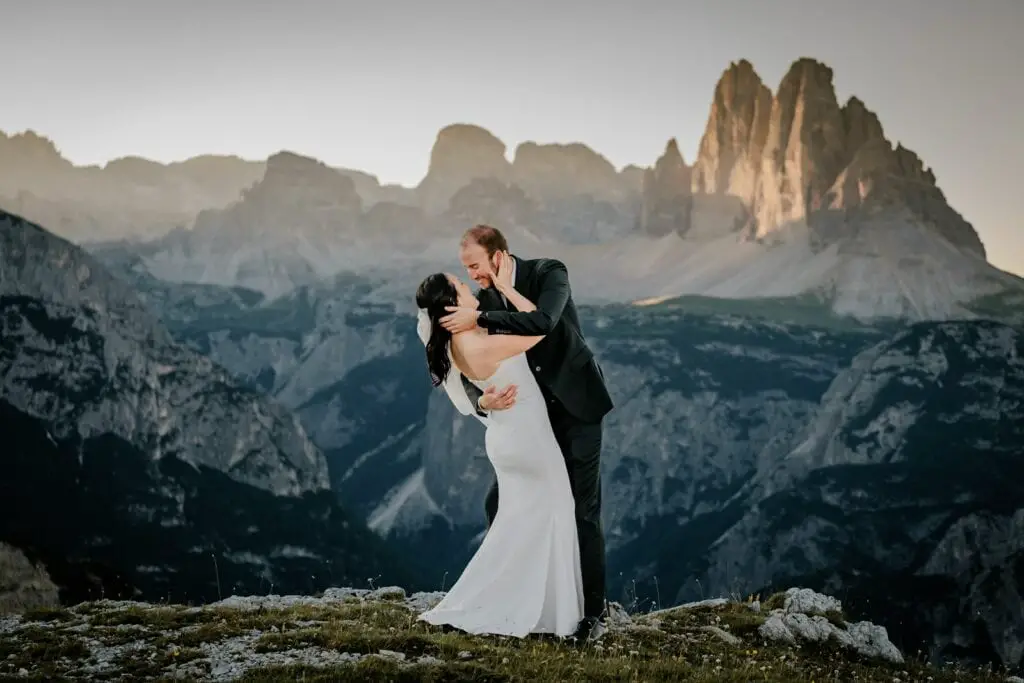 Groom dips his bride with a mountain panorama of the Dolomites in the distance