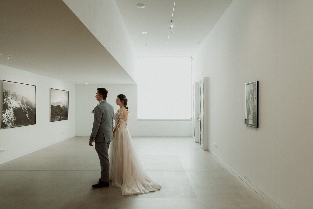 Bride and groom looking at a photo exhibition in the Lumen art gallery