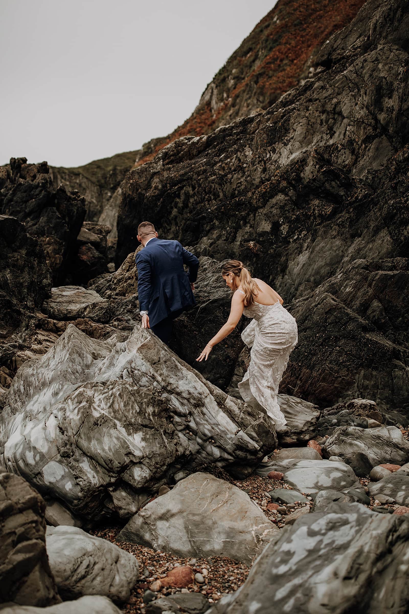 bride and groom are climbing up the cliffs in Ireland