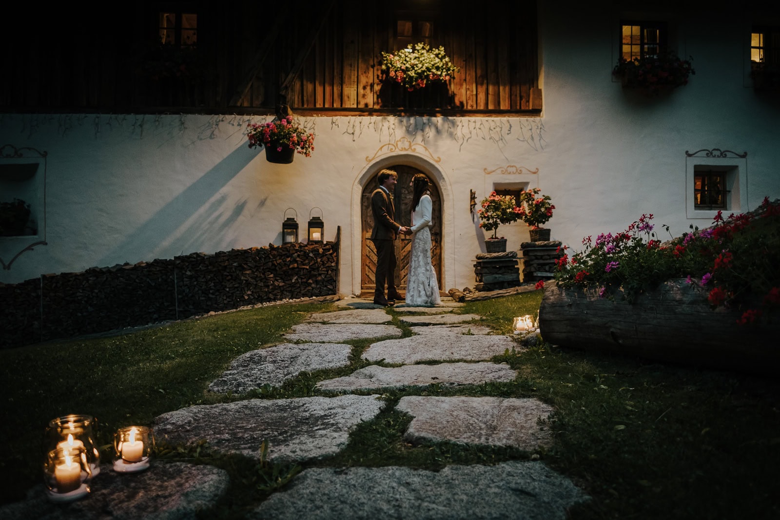 An intimate wedding on Seceda. Bride and groom stand in the meadow with the mountain as a backdrop and their families looking on.