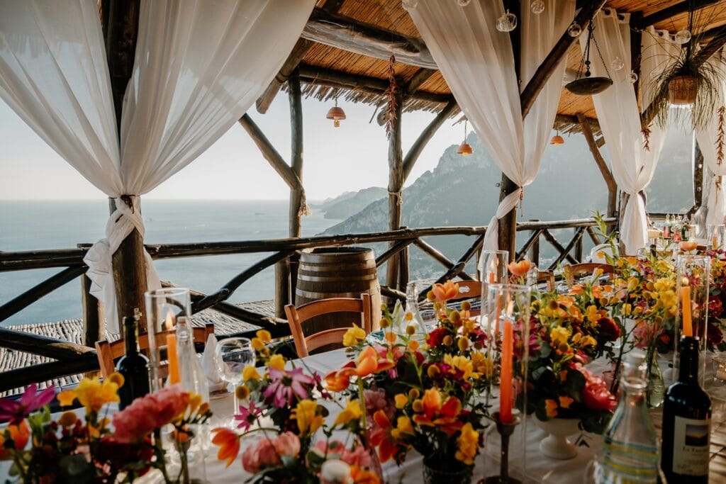 Wedding reception table with bright colorful flowers at La Tagliata, a restaurant overlooking the ocean in Positano, Italy