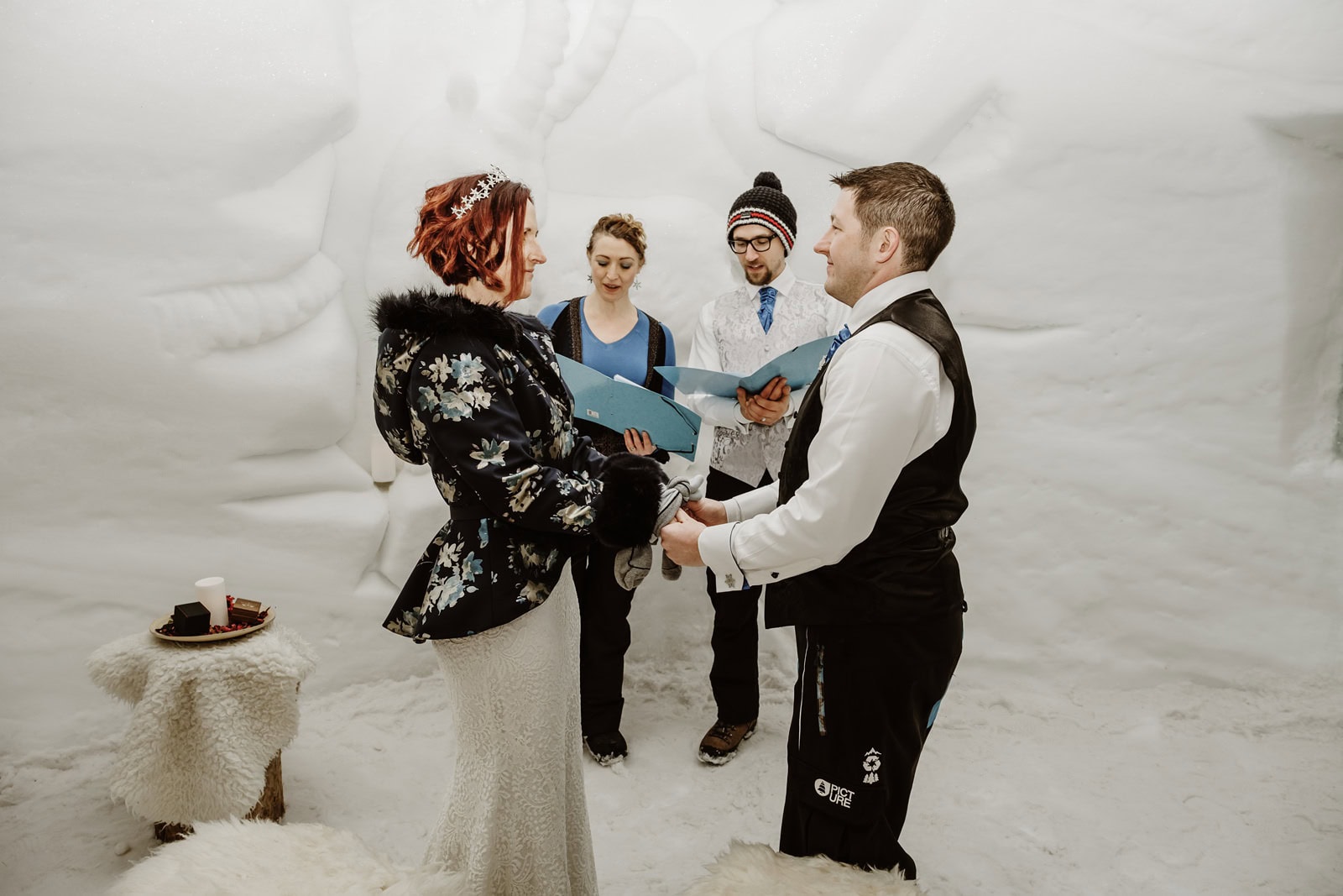 Wedding ceremony inside the White Lounge igloo in Mayrhofen in Austria, bride and groom stand facing each other holding hands.