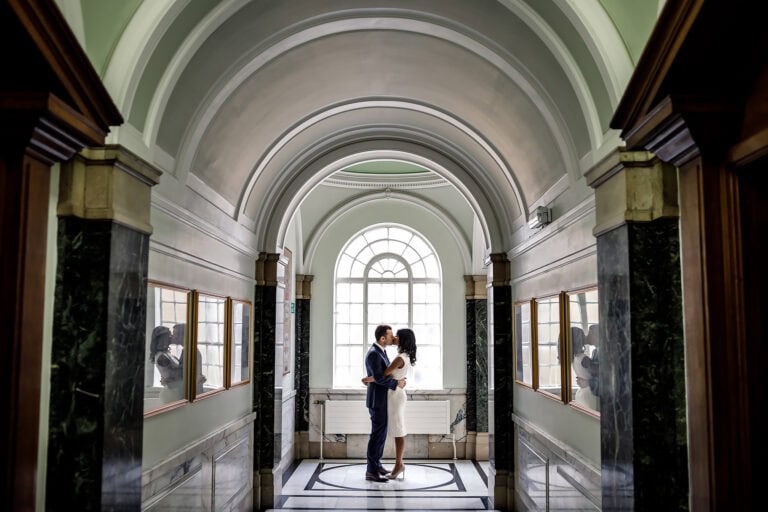 Bride and groom kissing in the marble hallway of Islington town hall