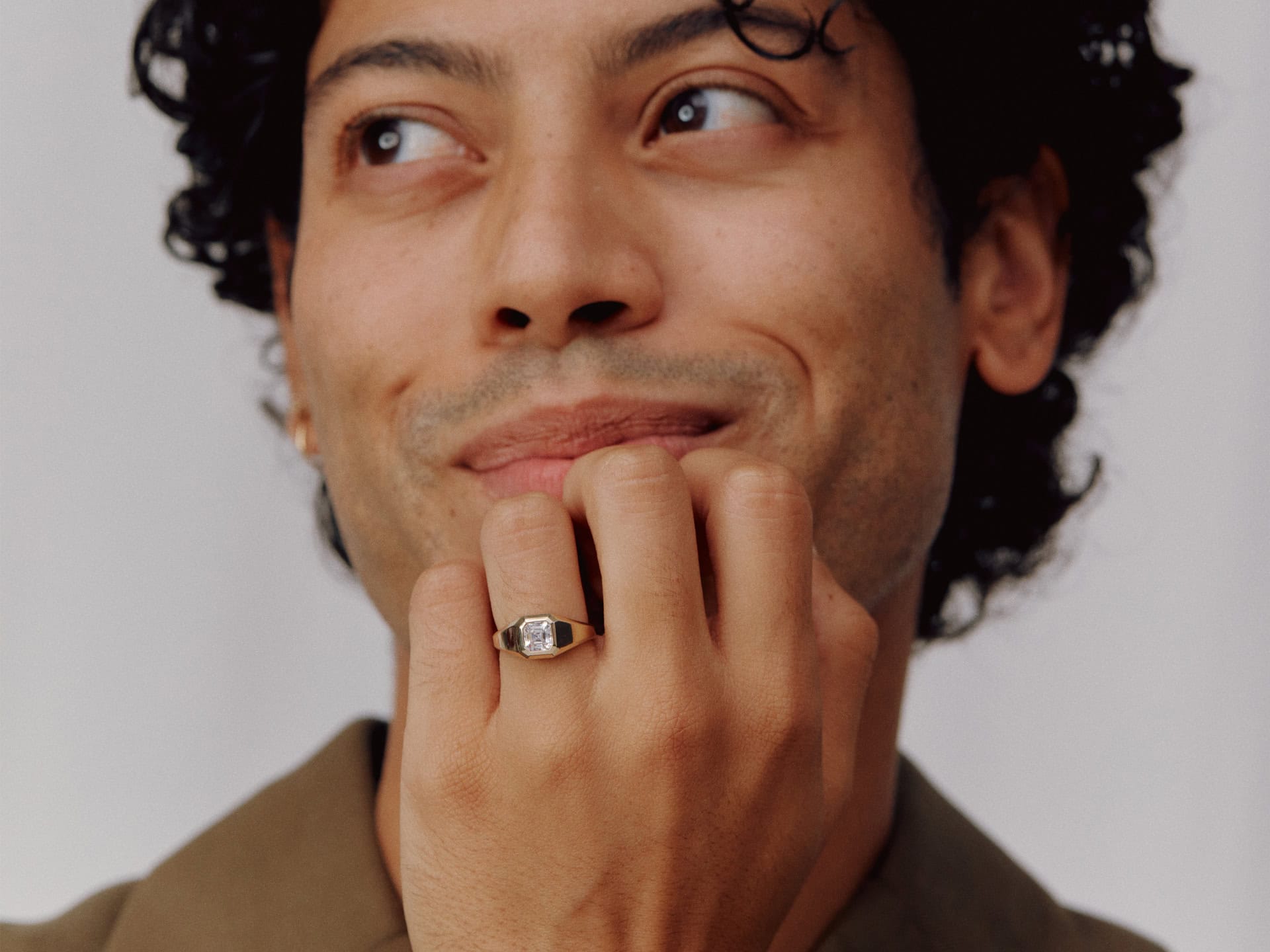 Male model wearing gold diamond signet ring and holding hand up to chin