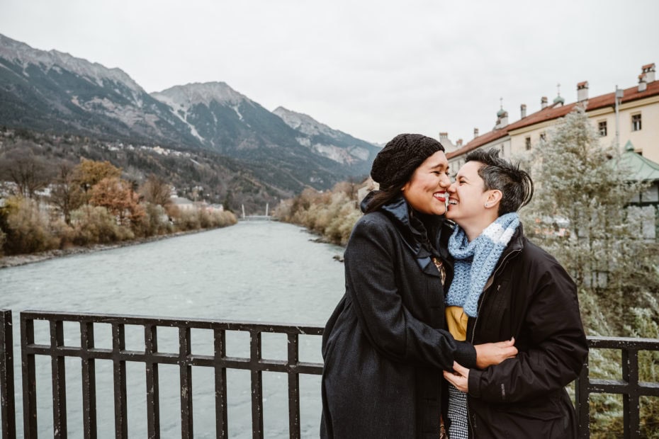 LGBTQ couple hugging and laughing on the bride over the river Inn in Austria
